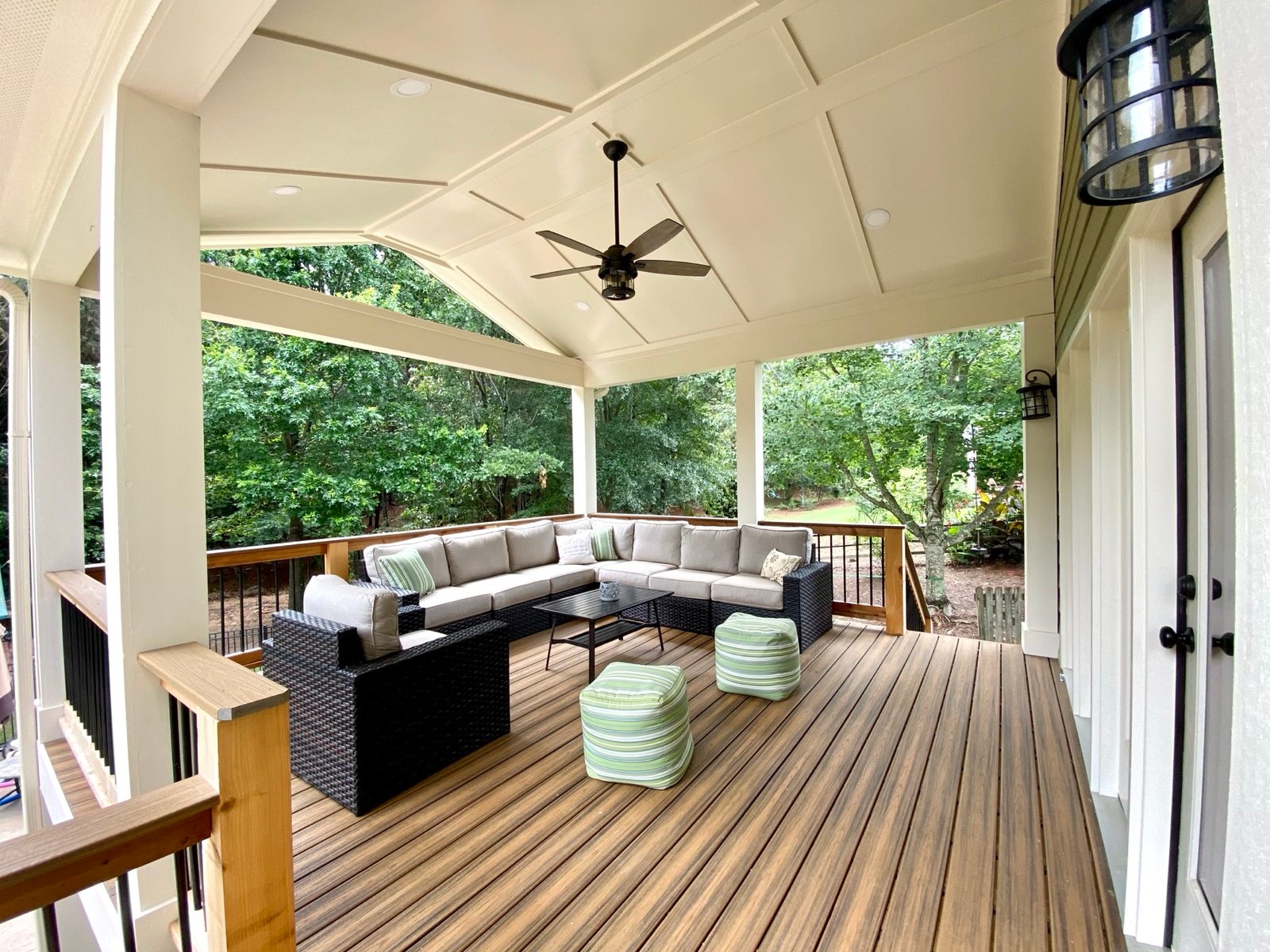 Covered deck outdoor living room open to the woods by GHIR Construction in Cumming, GA